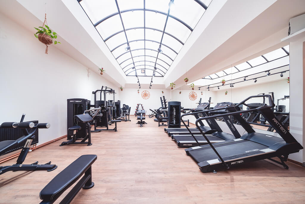 Hlavní sál posilovny MyGymTime s prosklenou střechou a posilovacími stroji